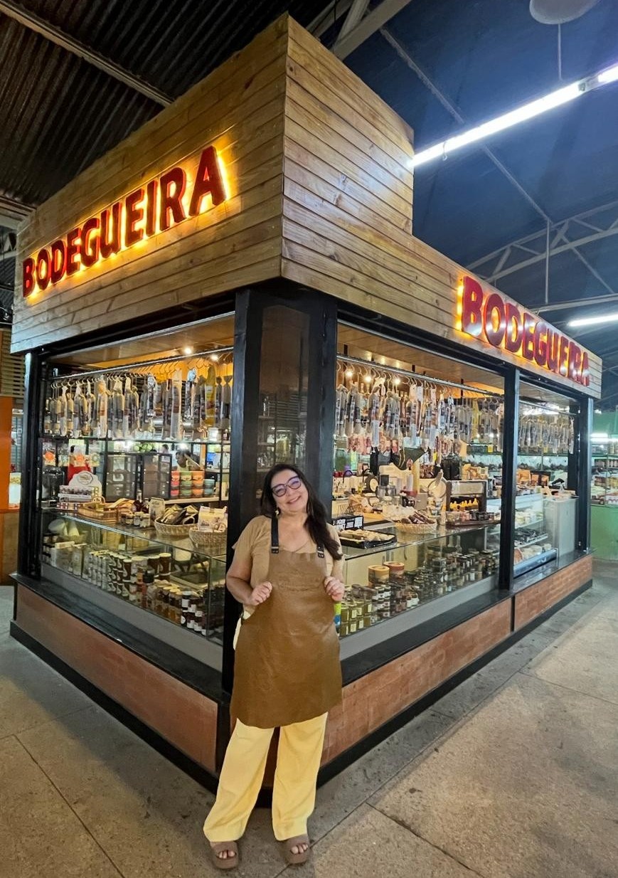 Foto da bodegaria mostrando seus produtos (queijo, salames e geleias) e atendentes em ação.